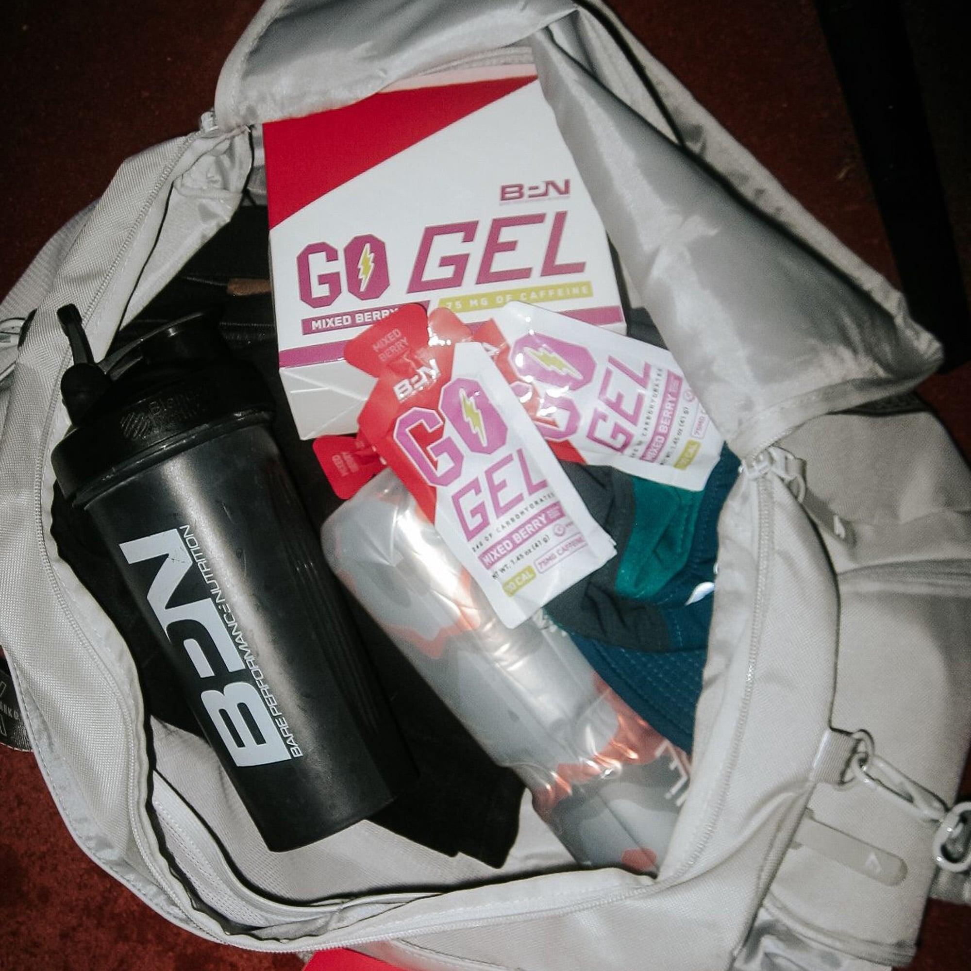 Gym bag with energy gel packs, a shaker bottle, and other fitness supplies.