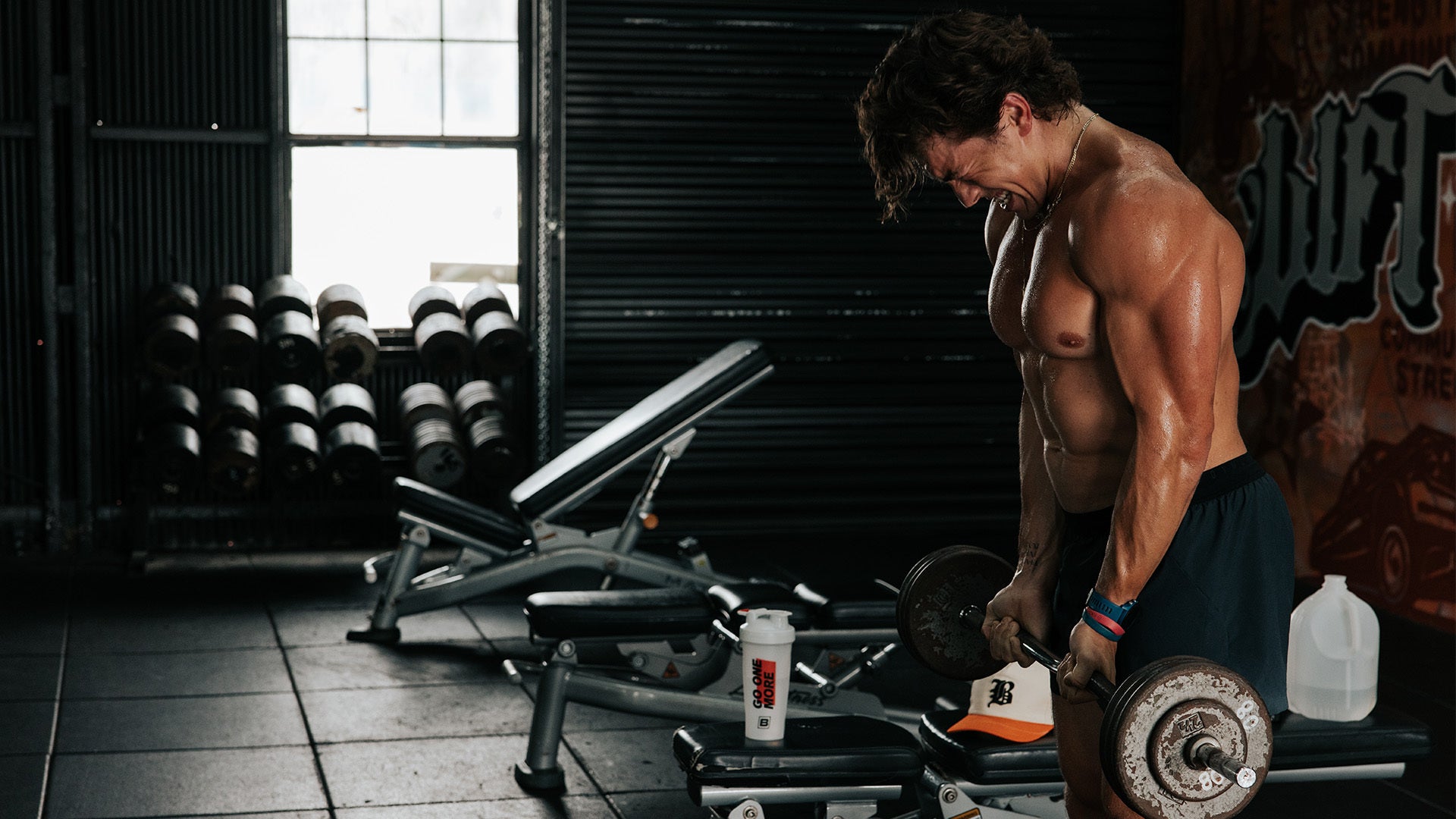 Man lifting weights in a dimly lit gym, showing intense focus and effort.
