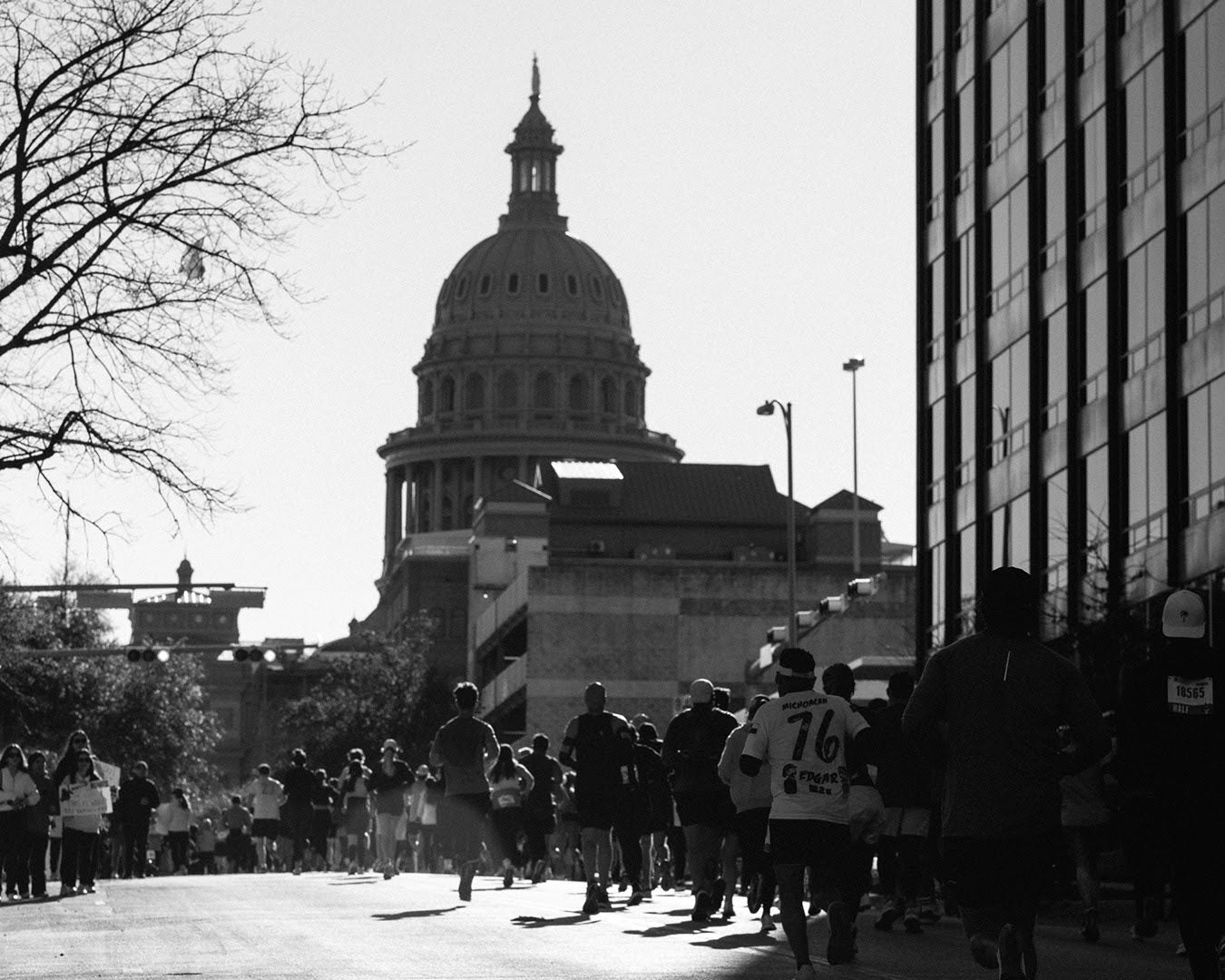 People running a street race towards a large domed building.