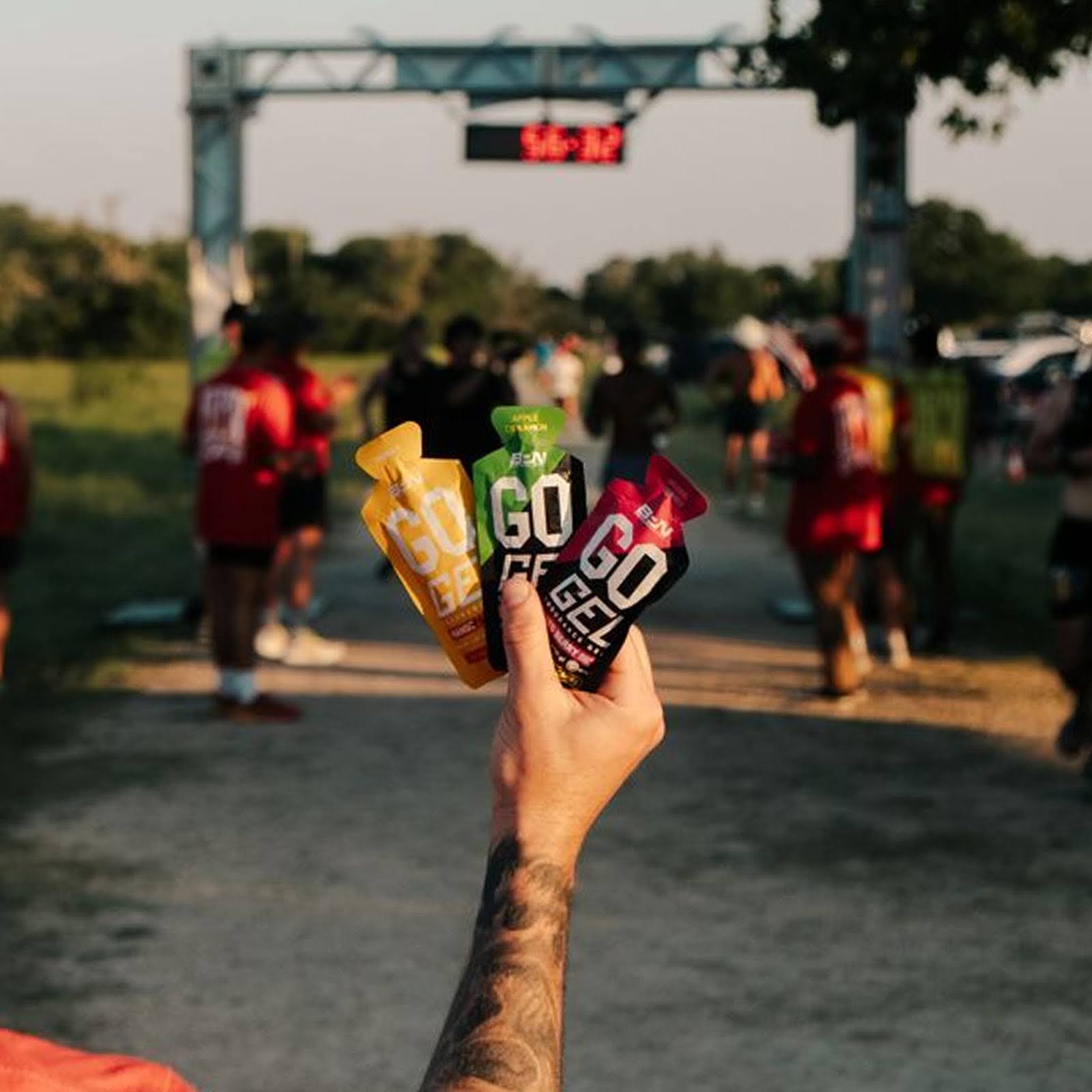 Runner holding three Go Gel packets at a race start line.